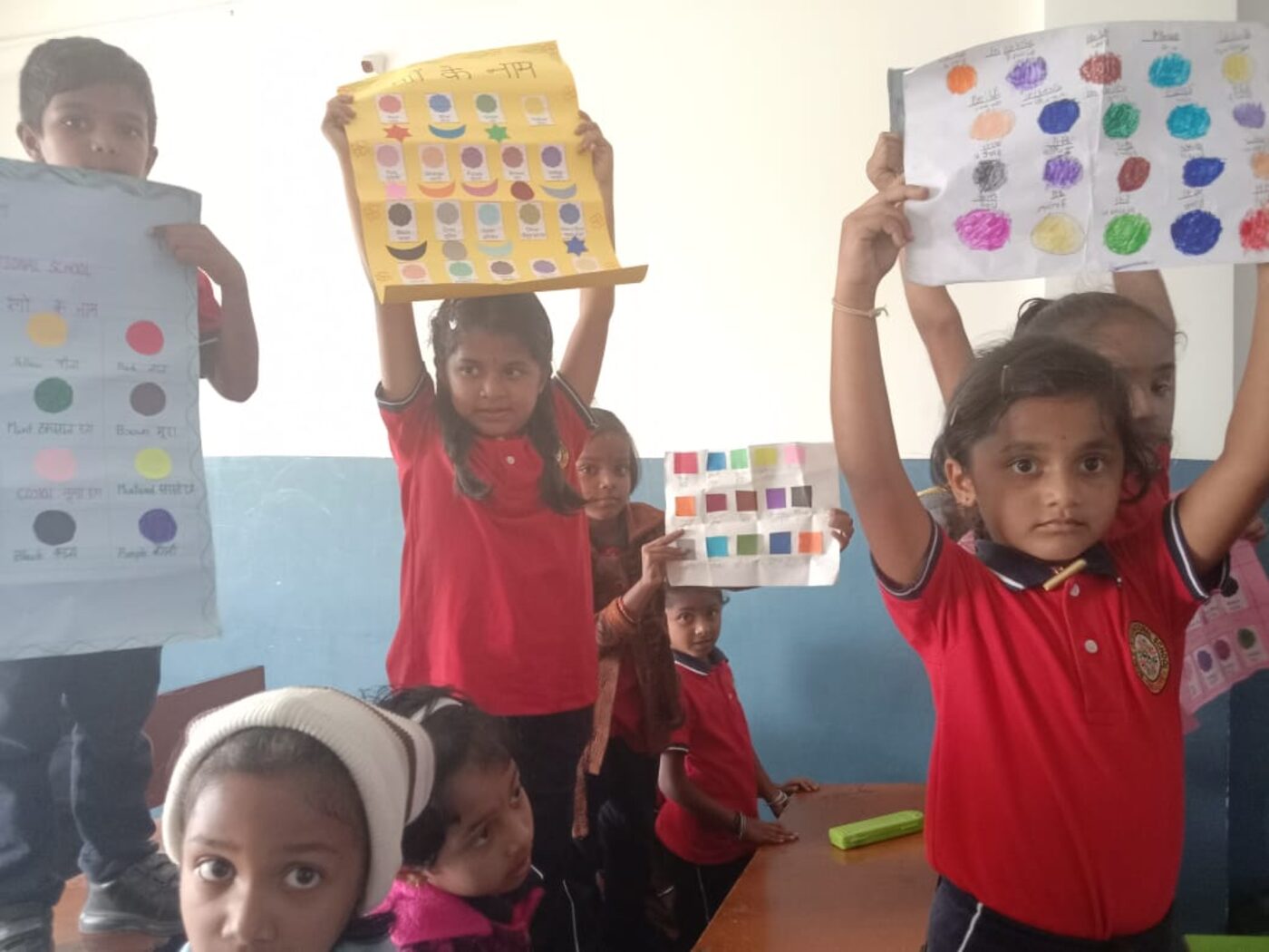 Children at Noble International School holding up their learning work